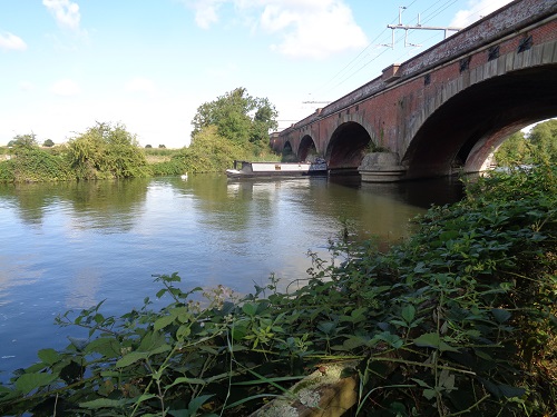 A narrowboat passing under the railway viaduct on The Thames